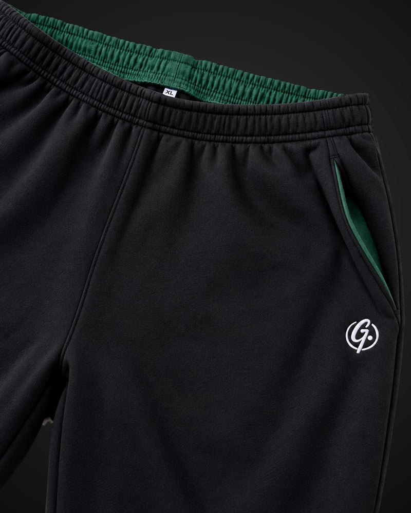 Elastic waistband of the black sweatpants with forest green lining and embroidered signet