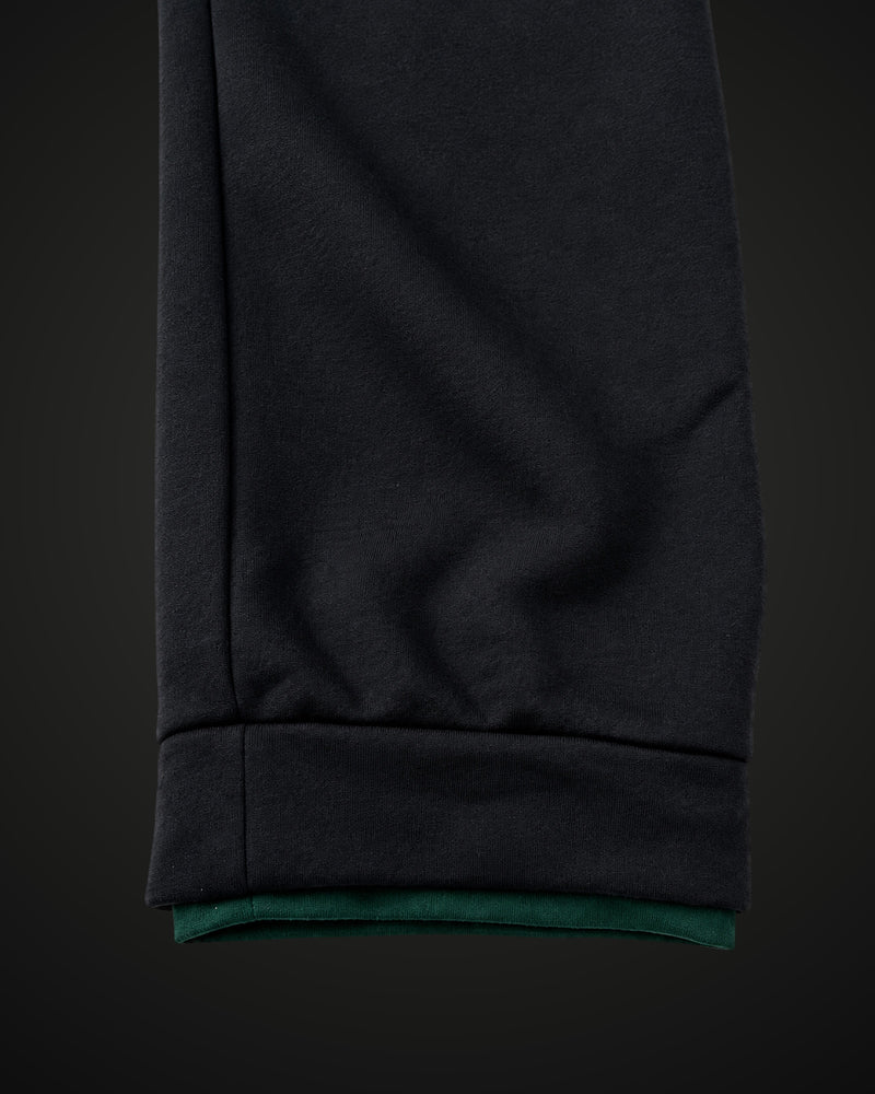 Cuffed hem of the black sweatpants with forest green edge