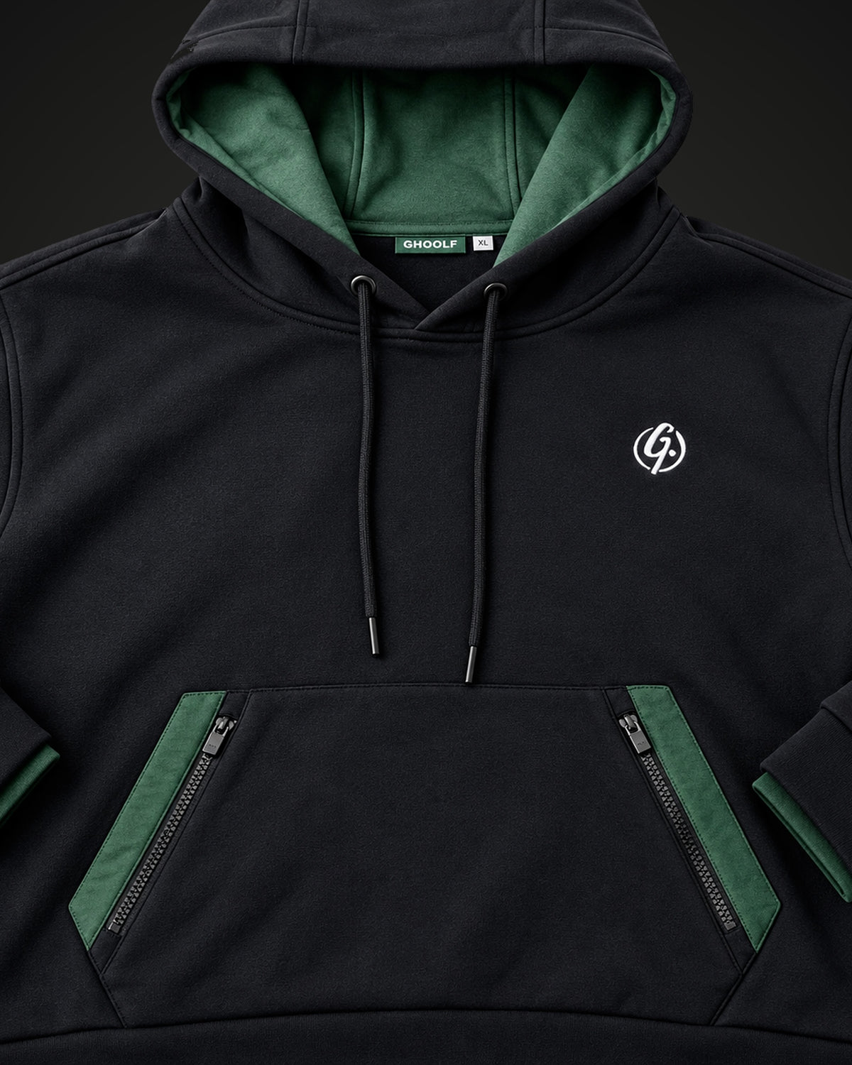 Front of the black hoodie showing two zip pocket openings framed in forest green
